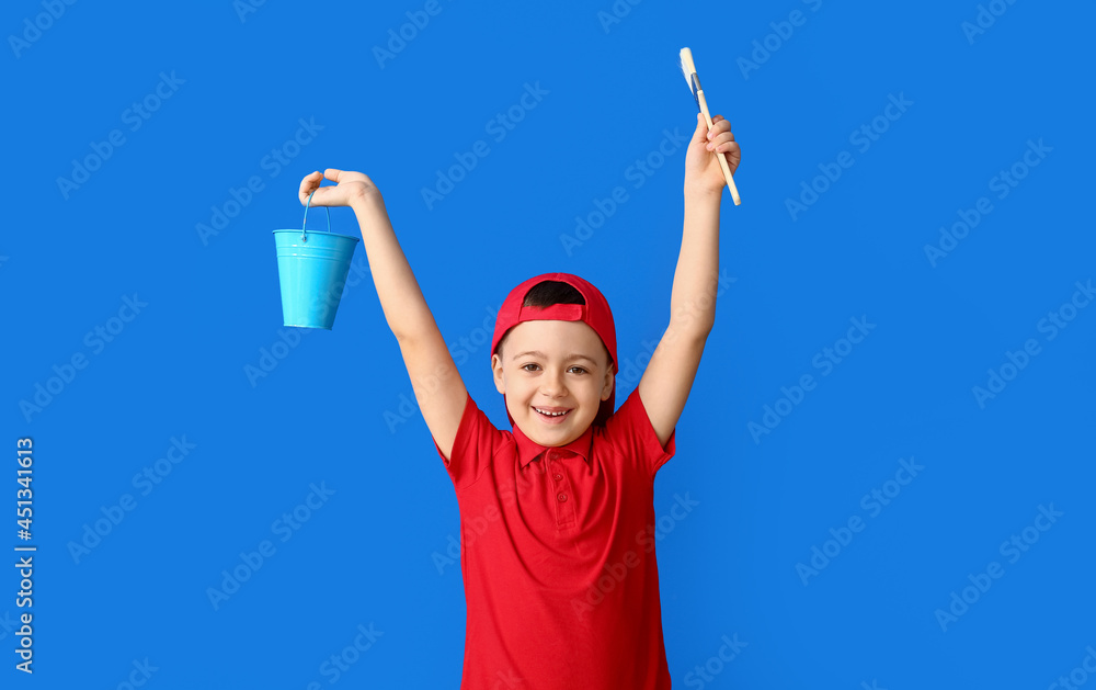 Little painter with bucket and brush on color background