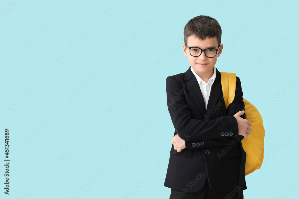 Little schoolboy on color background