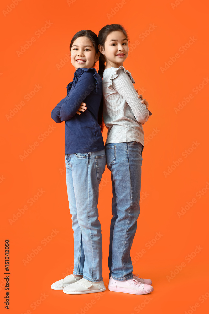 Cute little sisters on color background