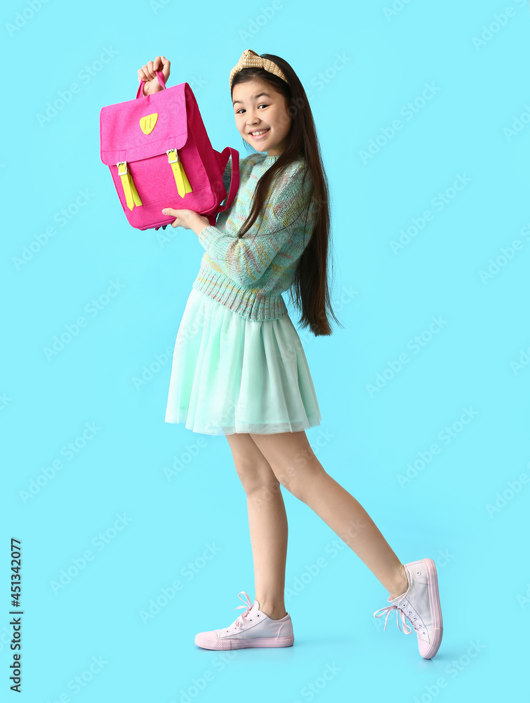 Cute little girl with stylish school backpack on color background