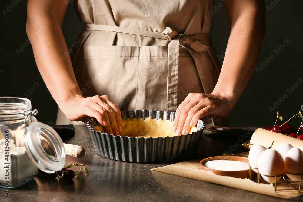 Woman cooking cherry pie at table