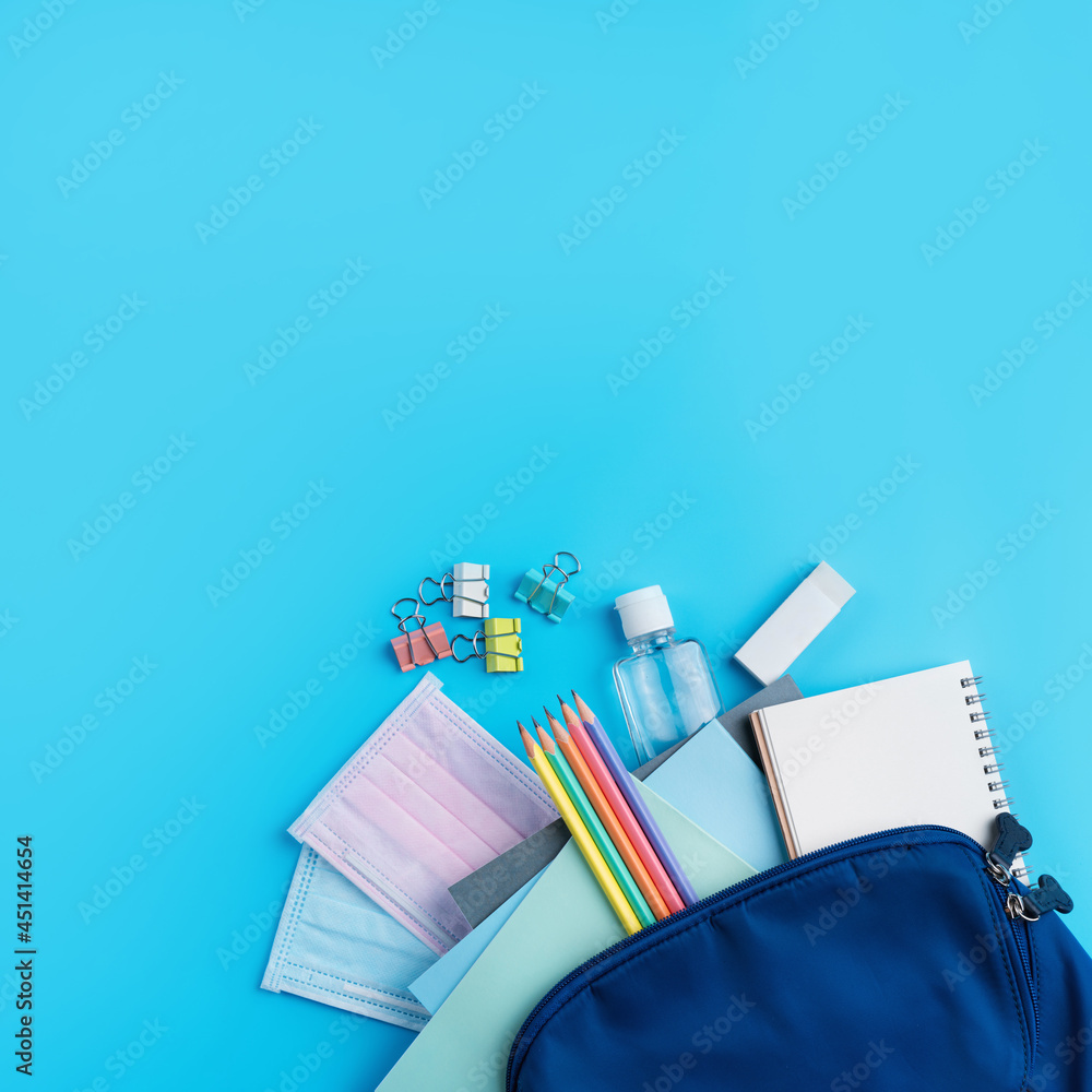 Blue backpack with stationery over blue table background.