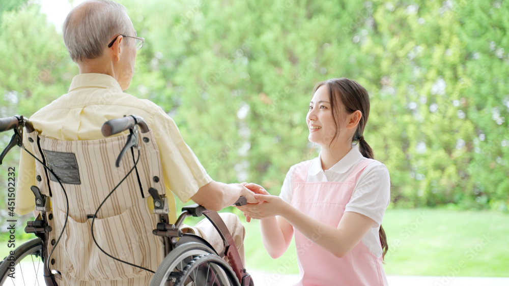 ヘルパーと話をする車椅子に乗った高齢の男性