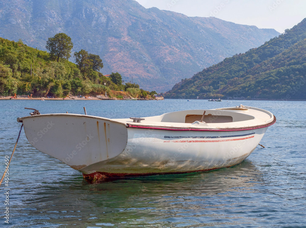 Boat on the water of the bay against the backdrop of wooded mountains.