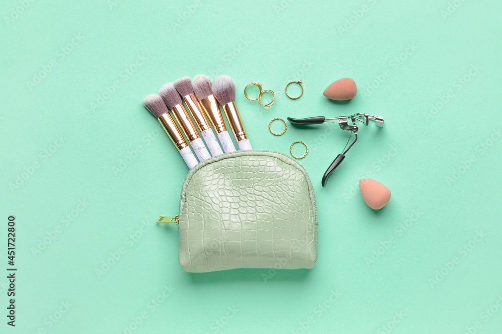 Stylish bag and decorative cosmetics on color background