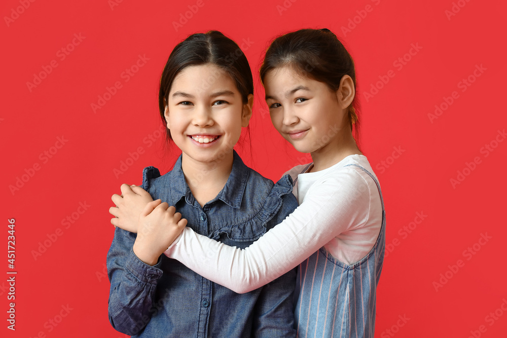 Cute little sisters on color background