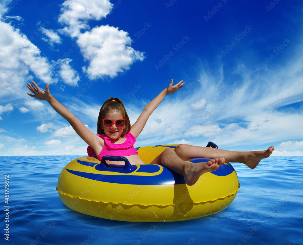  Little girl on inflatable ring in blue sea water