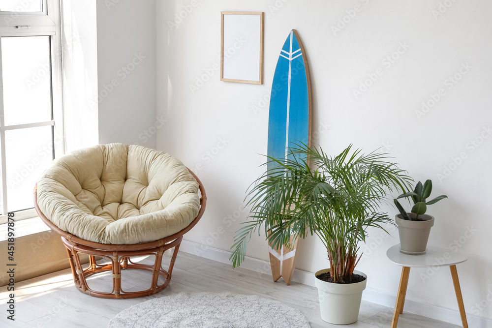 Interior of modern stylish room with surfboard, houseplants and armchair