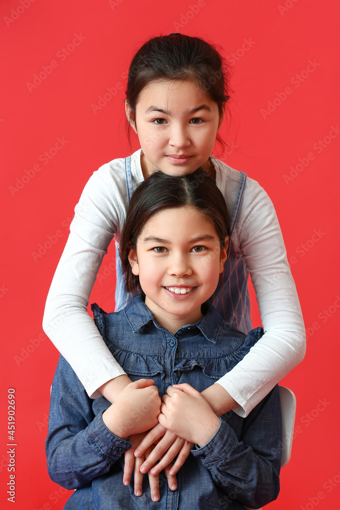 Cute little sisters on color background