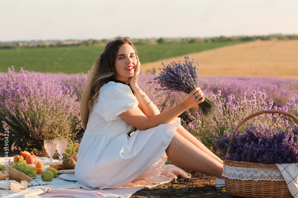 美丽的年轻女子在薰衣草地野餐