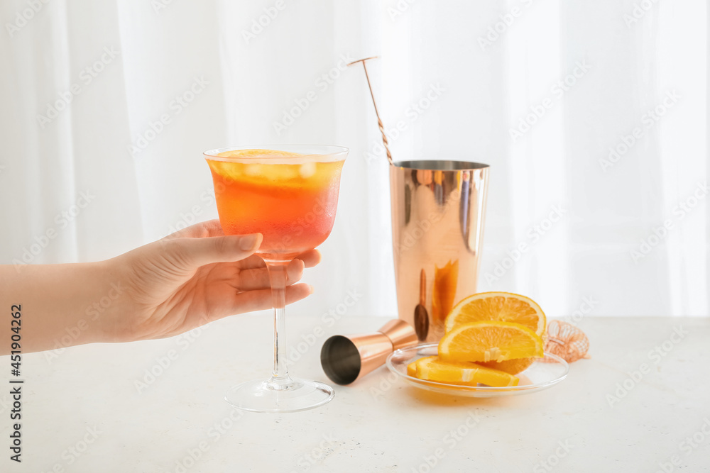 女性手拿一杯淡背景的Aperol雪碧鸡尾酒