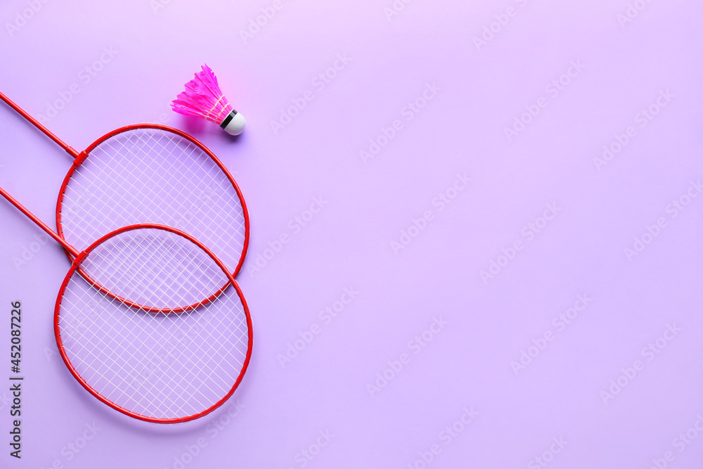 Badminton rackets and shuttlecock on color background