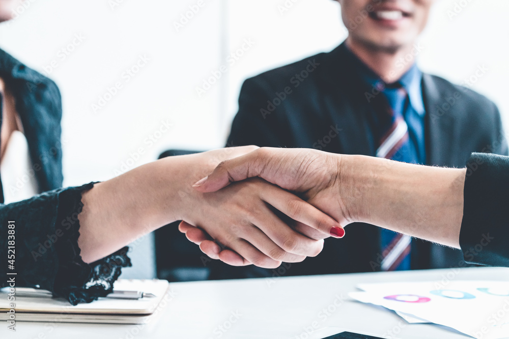 Business people agreement concept. Businessman and Asian businesswoman do handshake in the office.