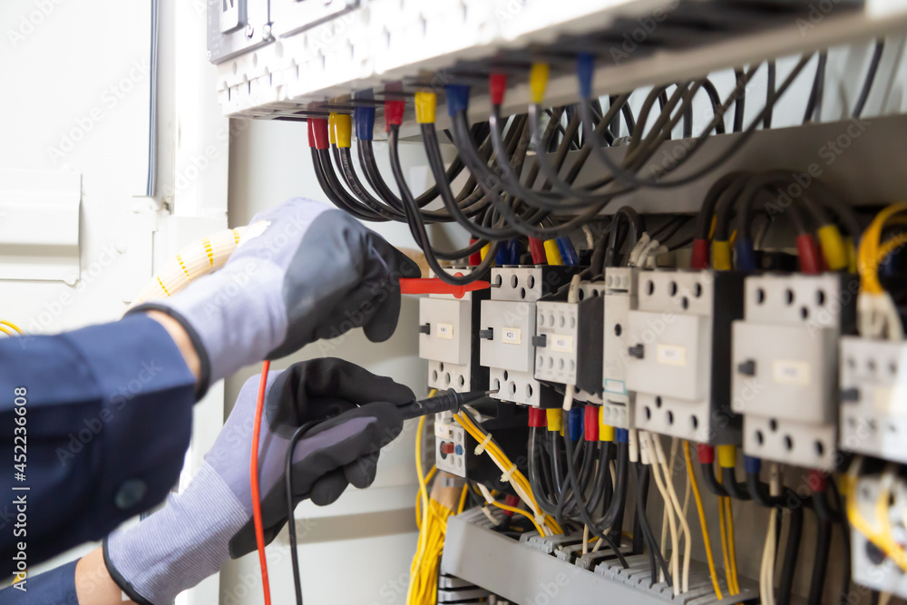 Electrician engineer tests electrical installations and wires on relay protection system. Adjustment