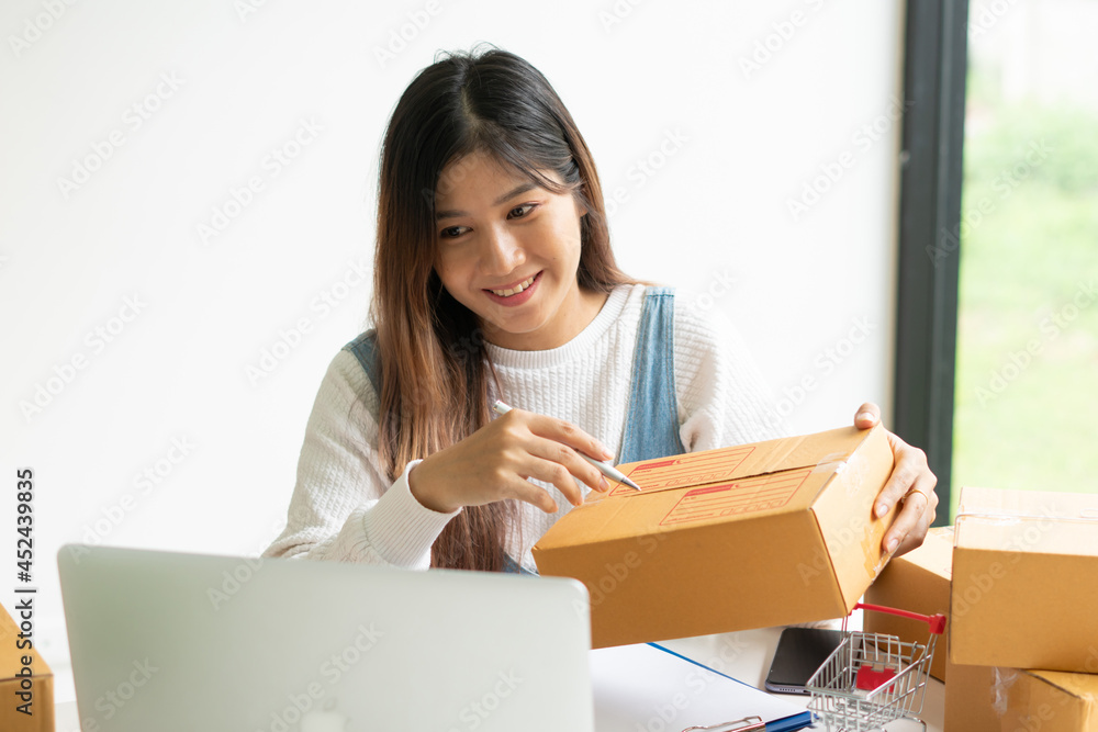 Young smiling beautiful owner asian woman freelance sme business online shopping working on laptop c