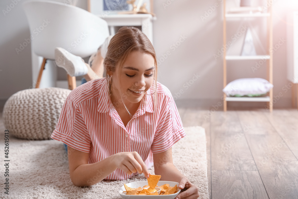 美丽的年轻女人在家吃美味的玉米片