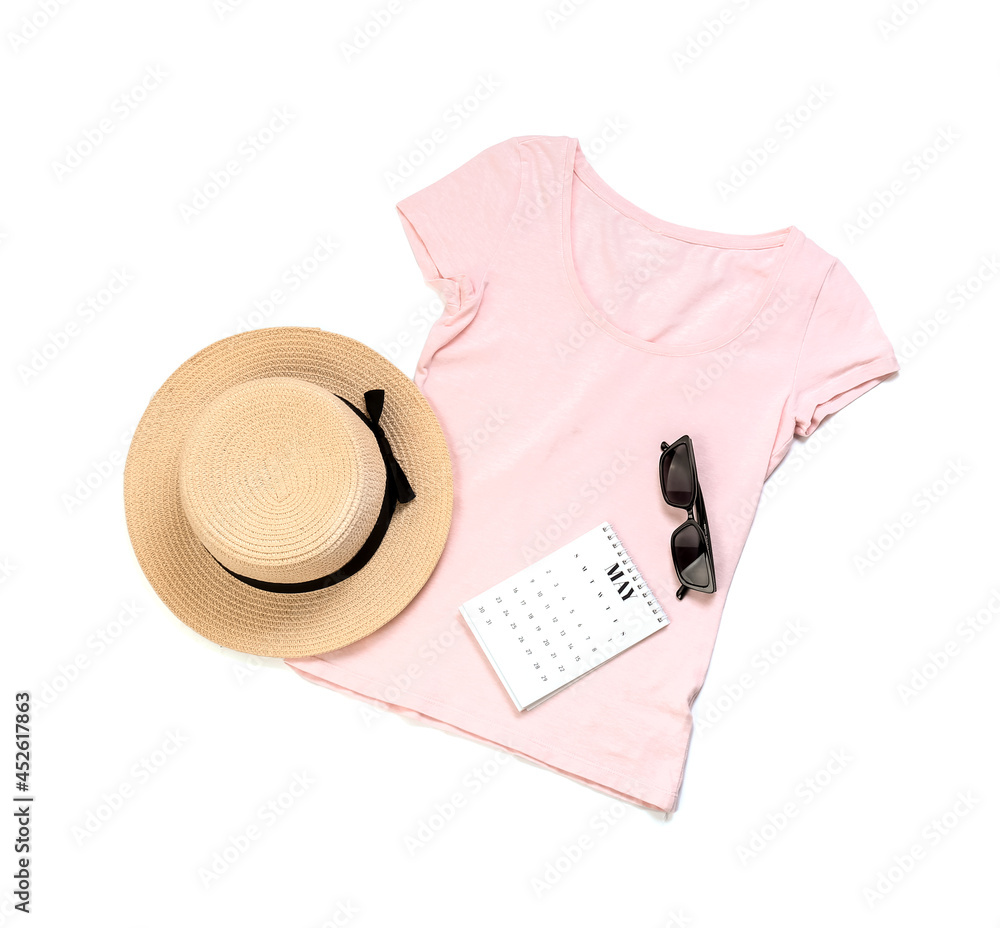 Stylish t-shirt, hat, sunglasses and calendar on white background