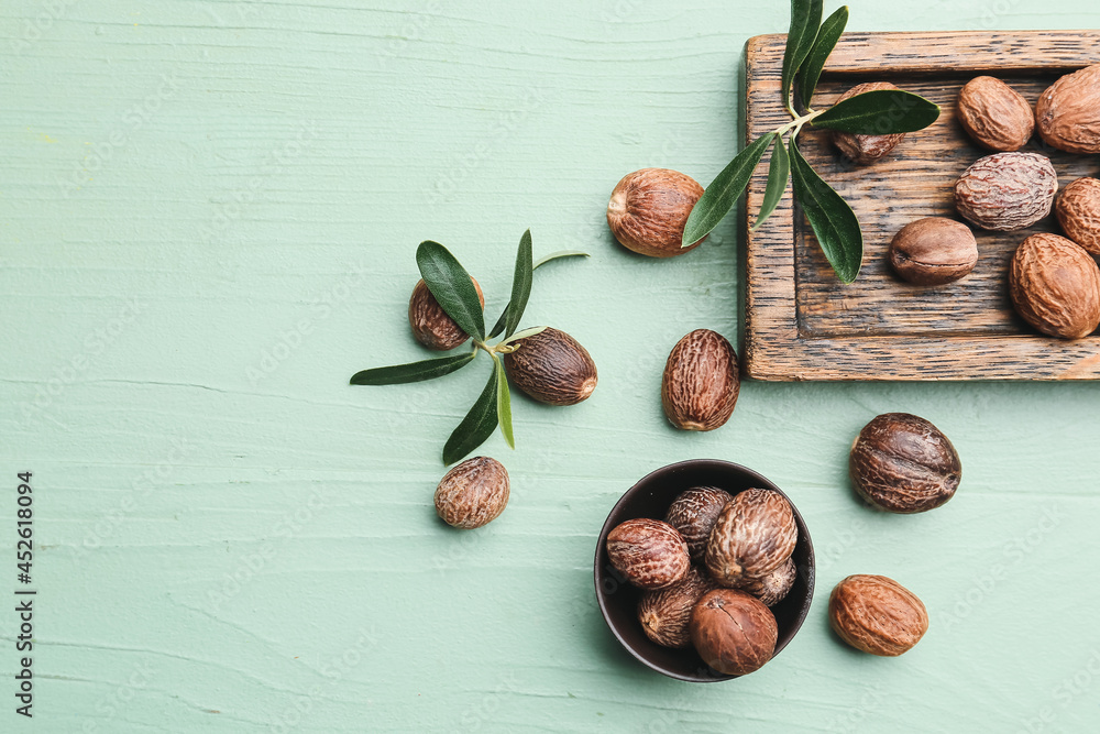 Bowl of shea nuts on color wooden background