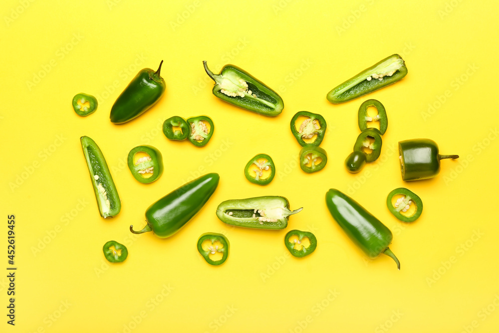 Cut green jalapeno peppers on color background