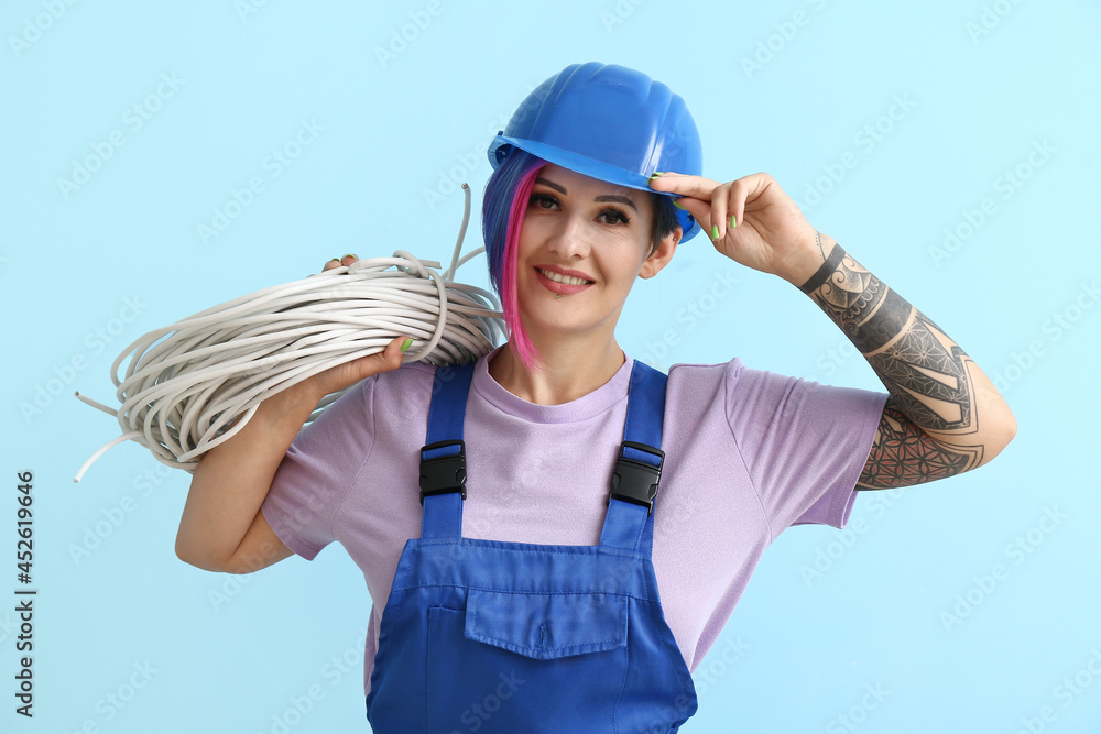 Female electrician with cables on color background