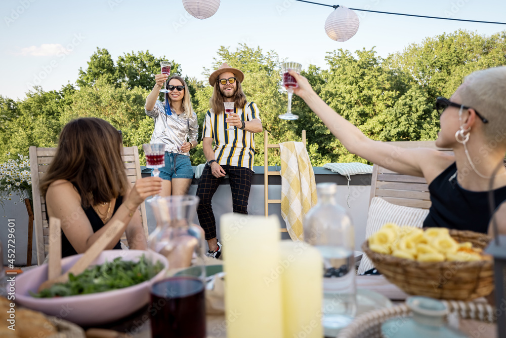 Group of young stylish people have a beautiful festive dinner outdoors. Friends talking and spending