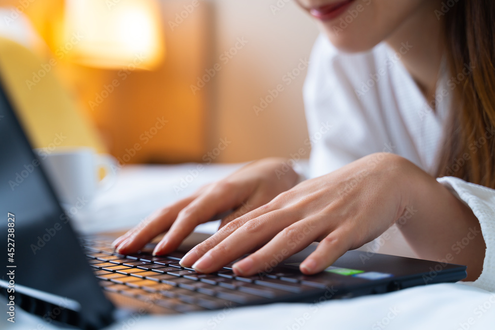 Portrait of Asian woman wearing bathrobe using a laptop for video call while have a morning coffee o