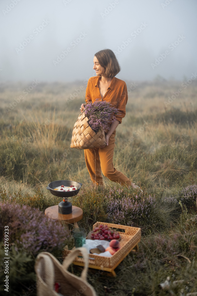 一个可爱的女人拿着刚摘下的石南花花束，在公园里吃早餐野餐的肖像