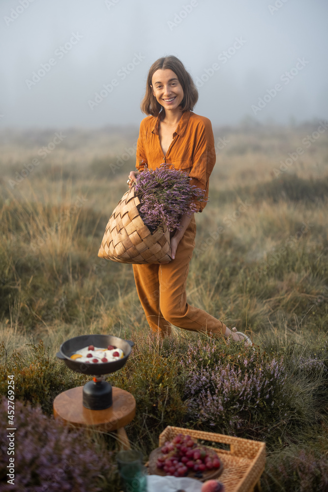 Portrait of a cute woman with a freshly picked up heather bouquet, having a breakfast picnic in the 