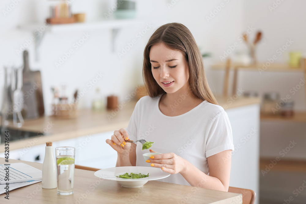 Beautiful young woman eating tasty ravioli at home