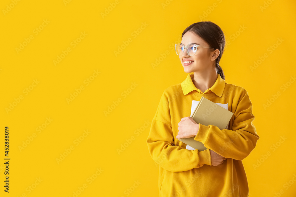 Young woman with books on color background