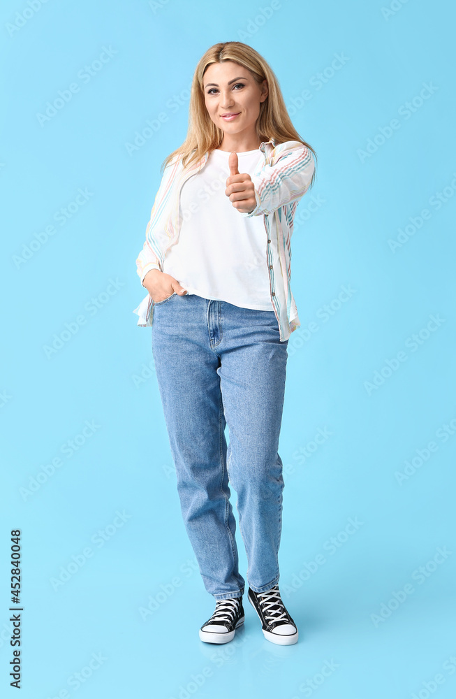 Portrait of stylish woman showing thumb-up on color background