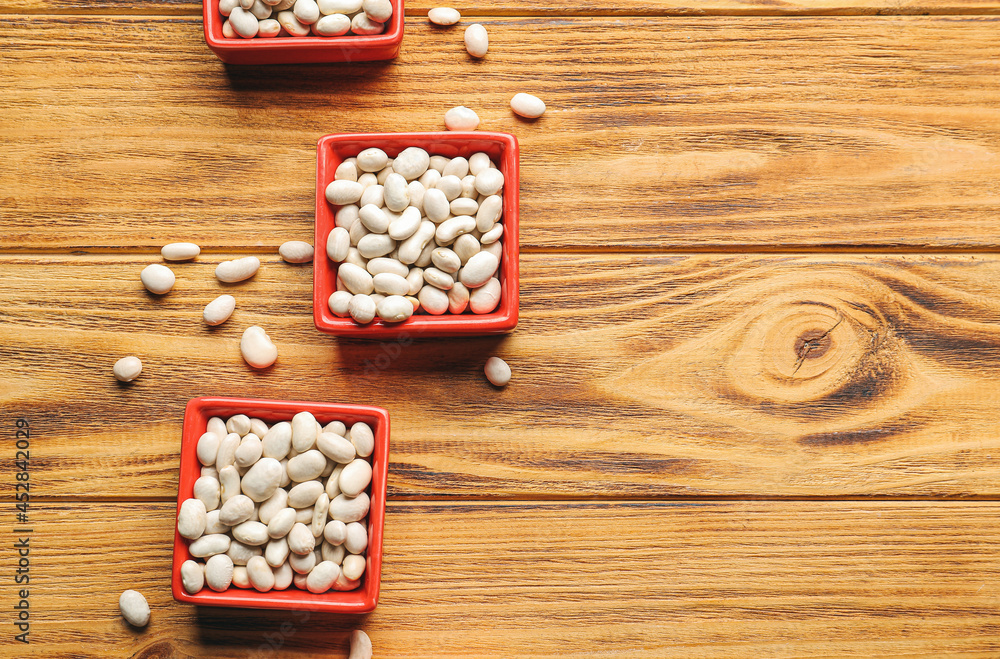 Bowls with raw beans on wooden background