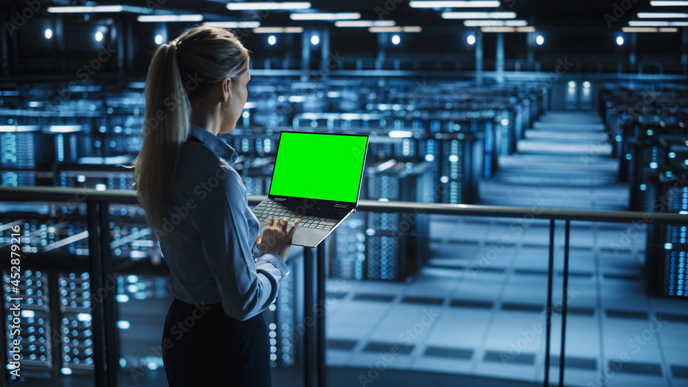 Female It Specialist Using Chroma Key Laptop in Data Center. Big Server Farm Cloud Computing Facilit