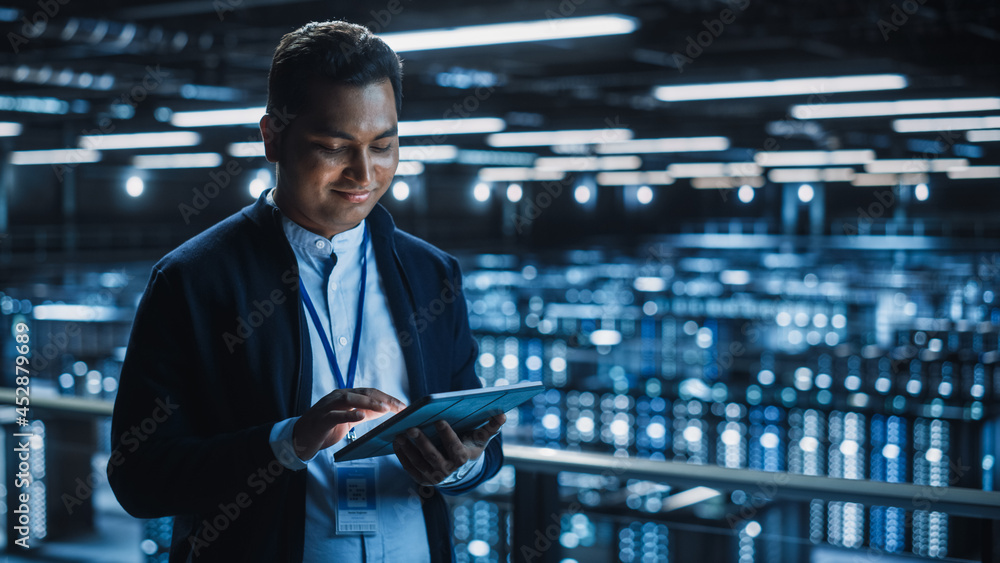 Handsome Smiling IT Specialist Using Tablet Computer in Data Center. Succesful Businessman and e-Bus