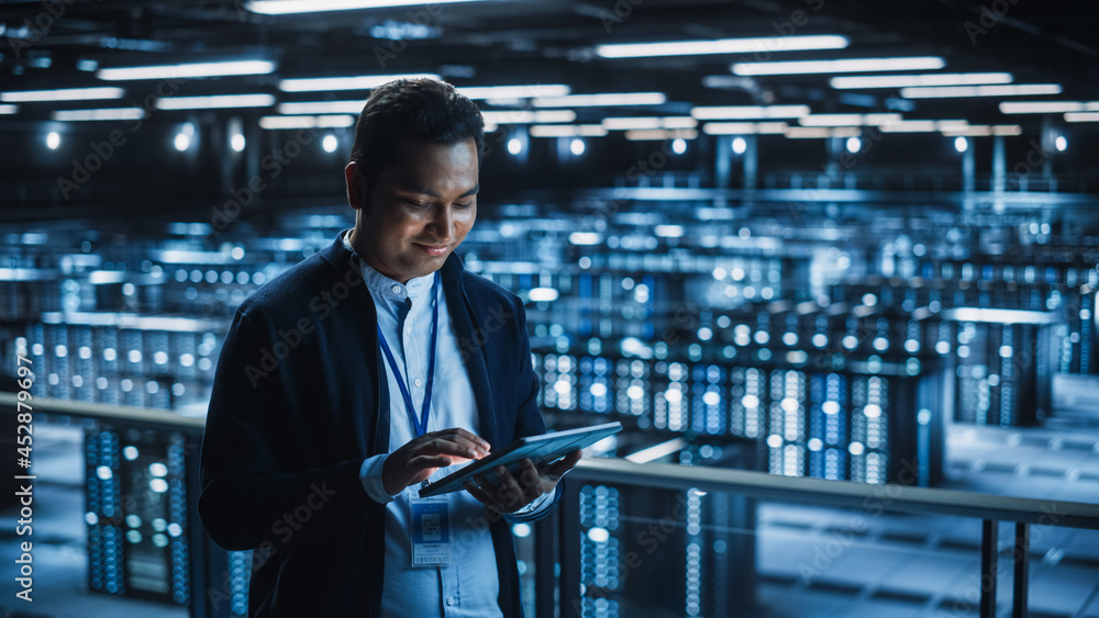 Handsome Smiling IT Specialist Using Tablet Computer in Data Center. Succesful Businessman and e-Bus