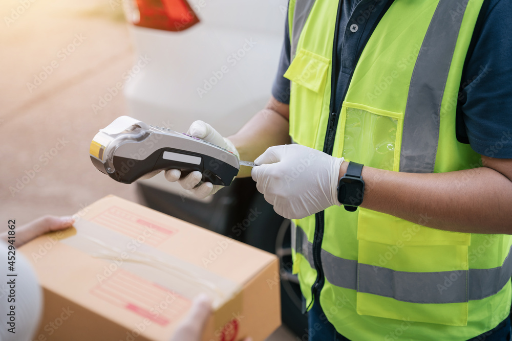 Close up hand of delivery man using a credit card reader while delivering products to customers at h