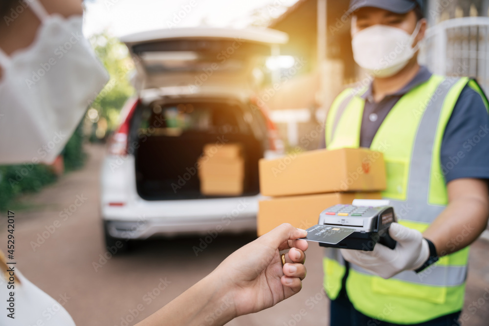 Asian delivery man using credit card swiping machine to pay. Hand with creditcard swipe through term