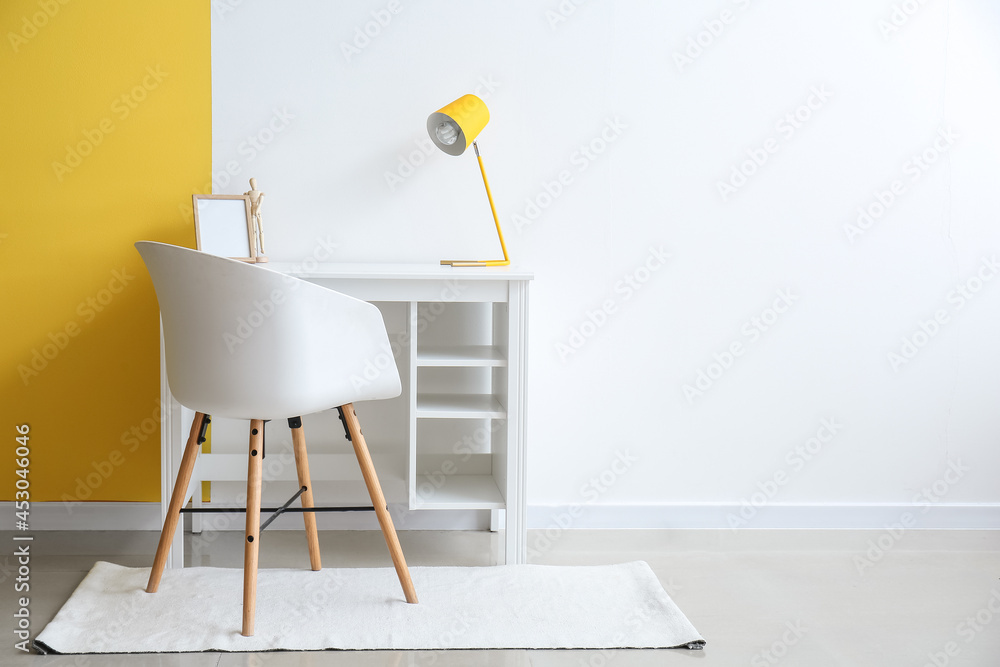 Modern workplace with lamp near color wall