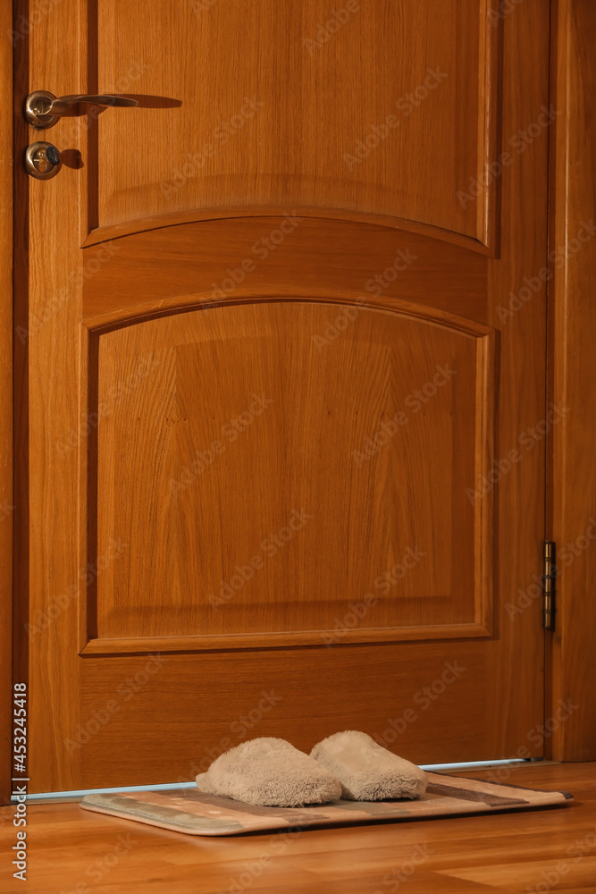 Female soft slippers on doormat at home