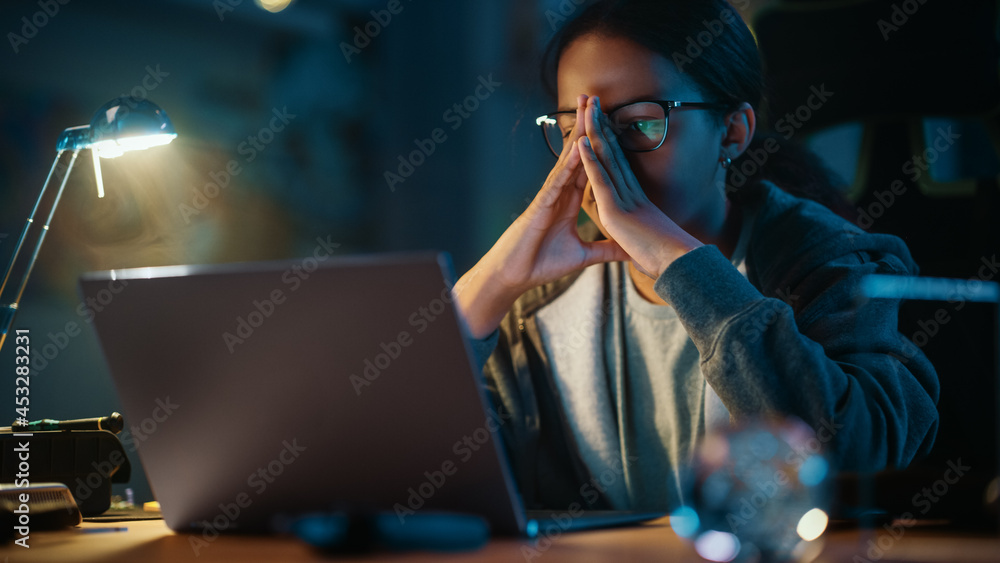 集中的年轻青少年多民族黑人女孩在家里黑暗舒适的房间里使用笔记本电脑。