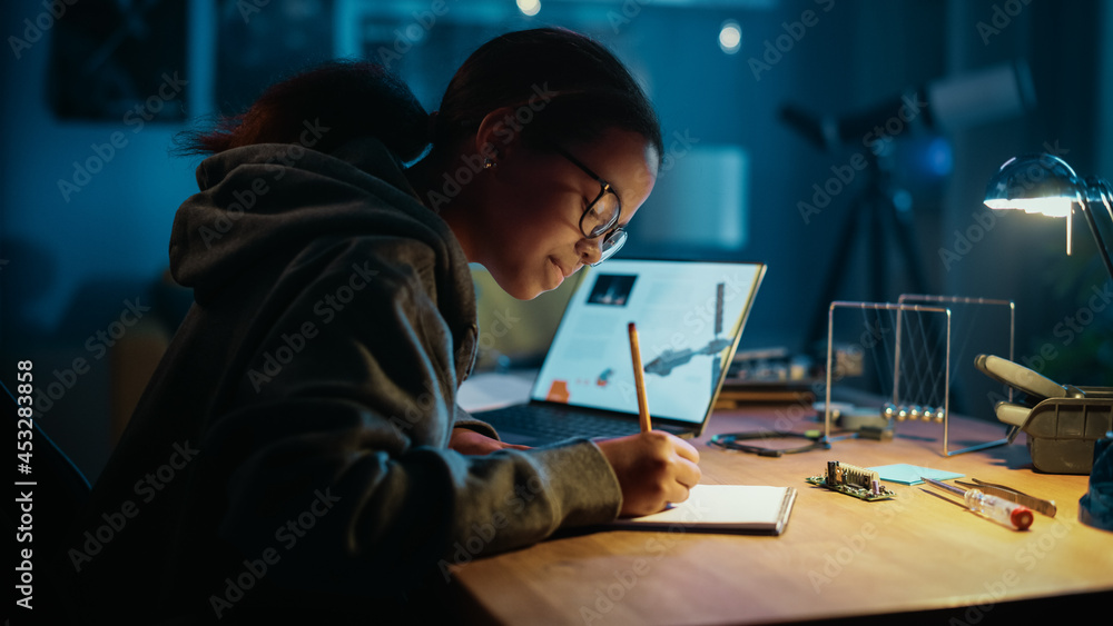 年轻的青少年多民族女学生在家学习关于机器人的科学主题。女孩是Worki