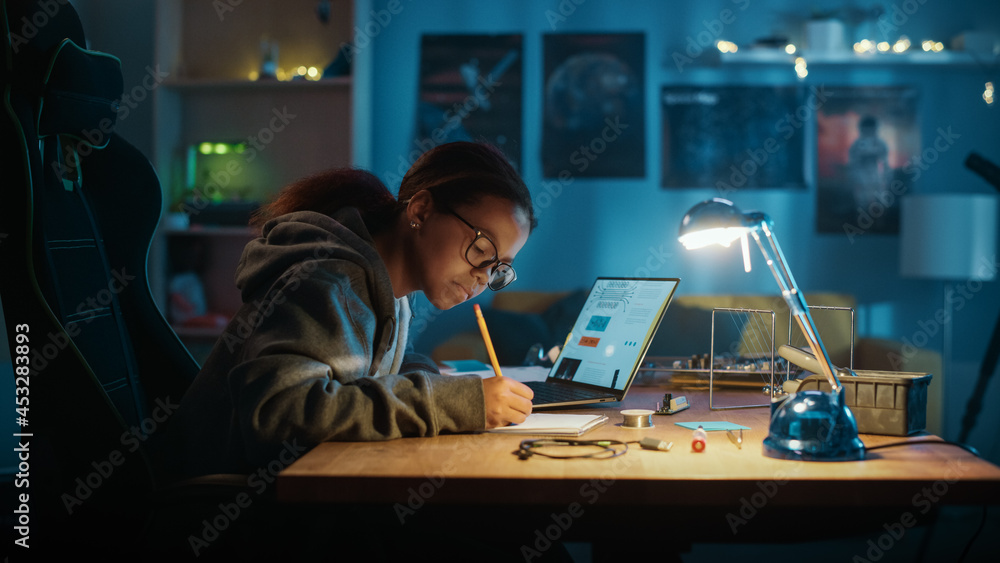 年轻的青少年多民族女学生在家学习关于机器人的科学主题。女孩是Worki