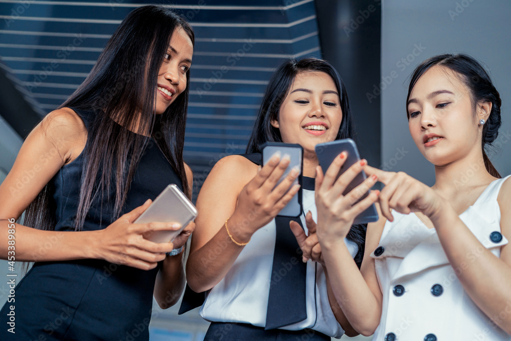 Three women friends having conversation while looking at mobile phone in their hands. Concept of soc