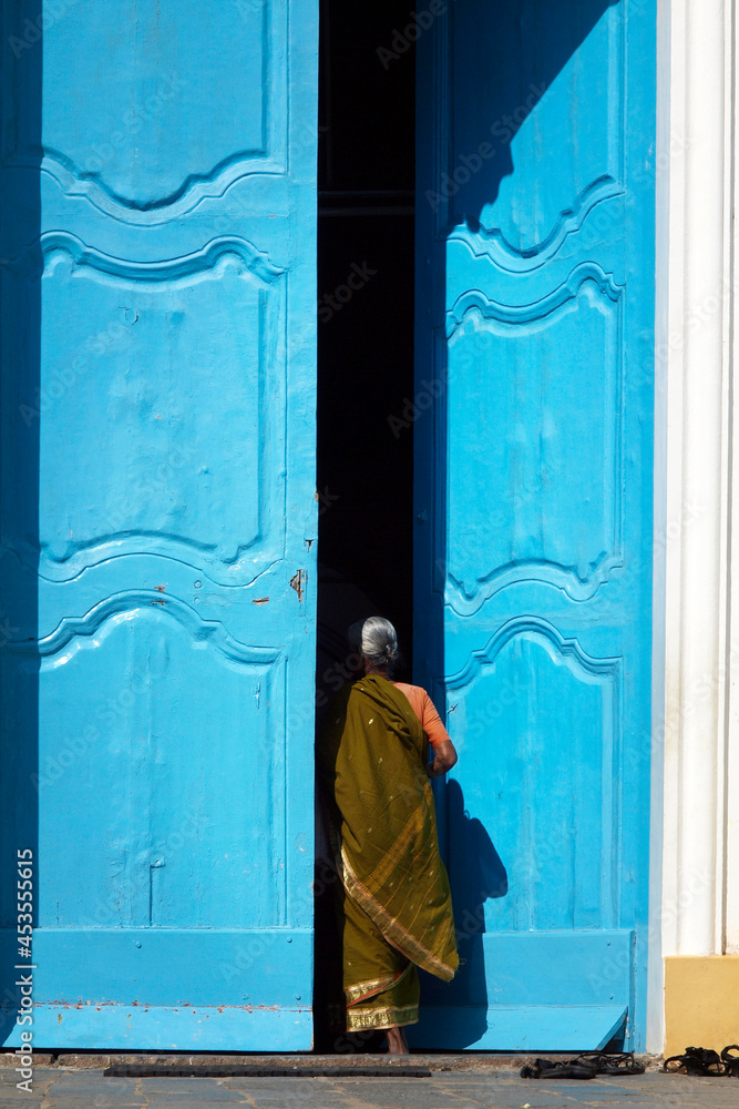 indian woman wearing saree entering through a large blue door