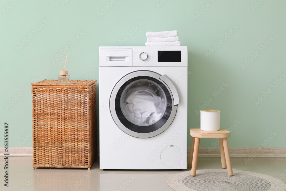 Modern washing machine with laundry in interior of bathroom