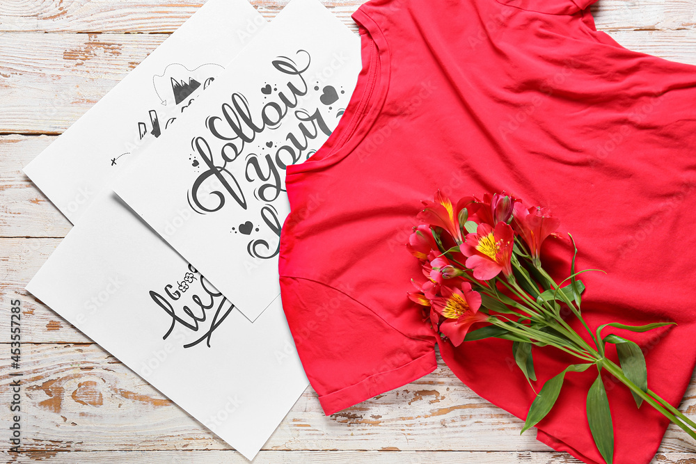 Composition with stylish t-shirt, flowers and greeting cards on light wooden background, closeup