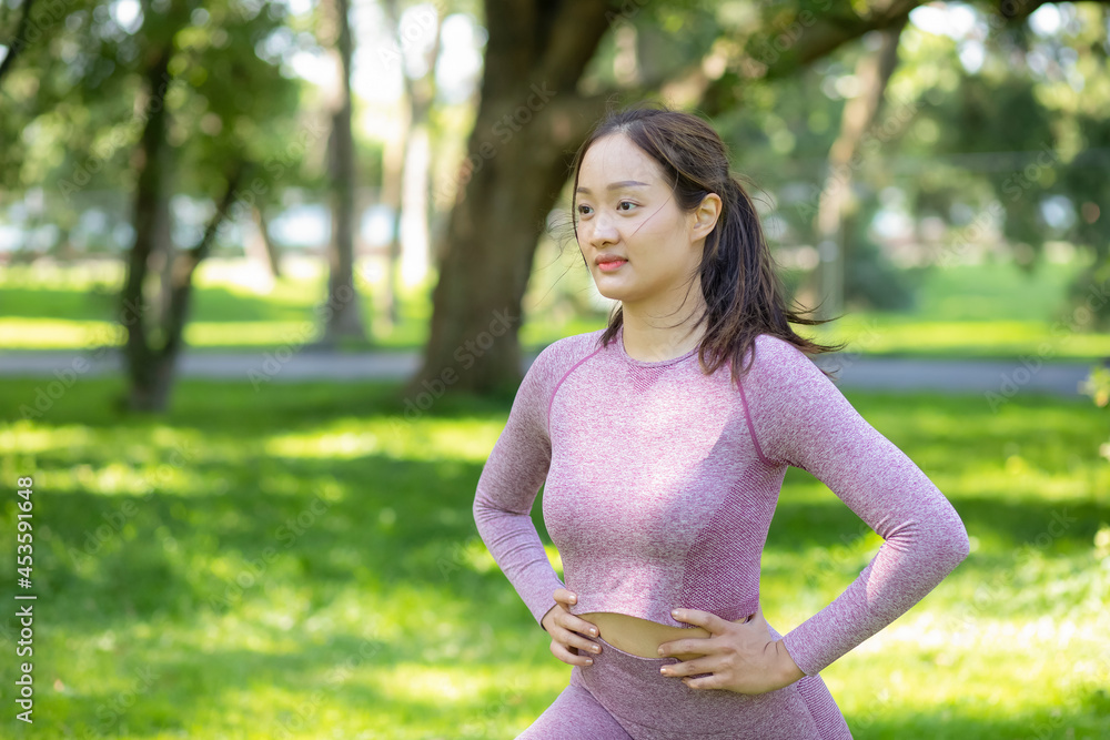 亚洲年轻女子在自然公园做瑜伽健身运动，锻炼身体或热身