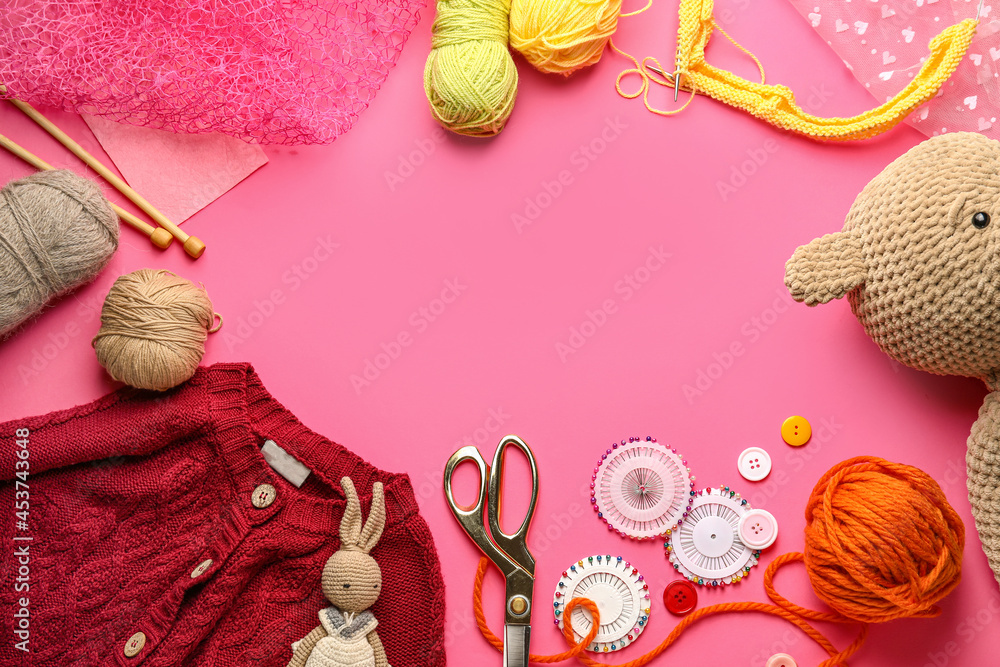 Frame made of knitting supplies, clothes and toys on color background