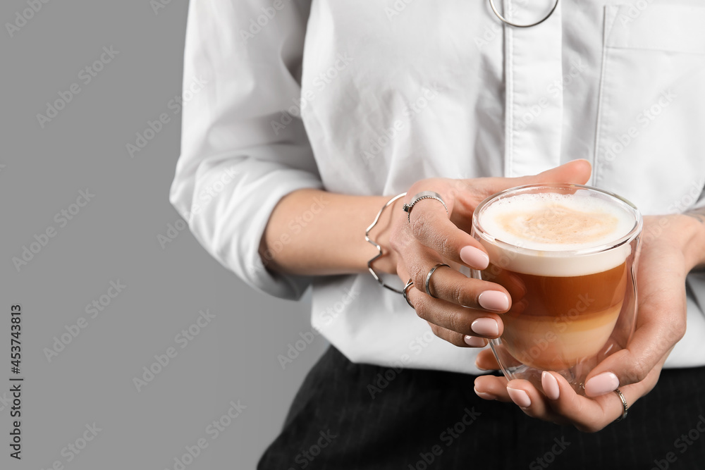 Woman drinking tasty coffee on grey background, closeup