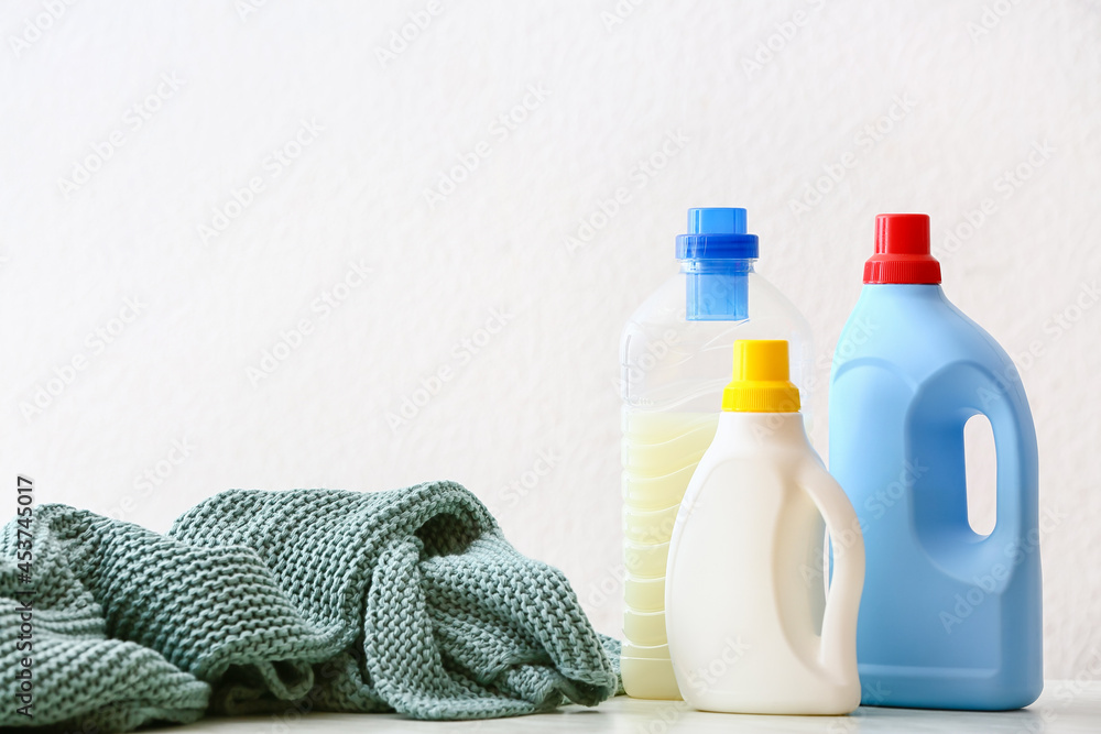 Knitted plaid and detergent on white background